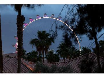 Exterior shot of Ferris wheel with palm trees and roof tile in foreground at night at 270 E Flamingo Rd # 131, Las Vegas, NV 89169