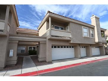 Beige townhome exterior with multiple garage doors, balcony, and well-maintained landscaping at 5125 W Reno Ave # 1059, Las Vegas, NV 89118