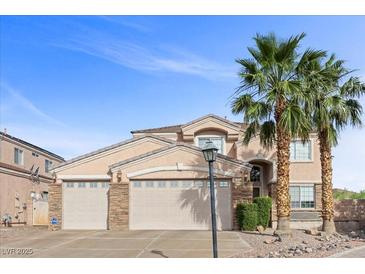 Inviting two-story home with a three-car garage, desert landscaping, and mature palm trees at 644 Wind Cave Ct, Henderson, NV 89012