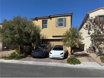 Two story home featuring neutral stucco, brick driveway, desert landscaping, and an attached two car garage at 8675 Scalpay St, Las Vegas, NV 89166