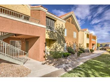Charming condo building featuring balconies, mature landscaping, and a tiled roof under a partly cloudy sky at 2120 Ramrod Ave # 2216, Henderson, NV 89014
