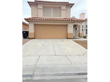 Two-story tan home with an attached two-car garage and mature landscaping in front of the house at 5040 Jacarilla Ln, North Las Vegas, NV 89031