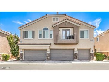 Two-story townhouse with three garages, neutral paint, and a small, charming balcony at 8775 Traveling Breeze Ave # 102, Las Vegas, NV 89178