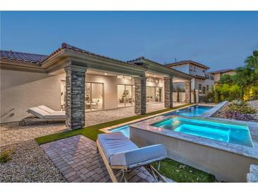 Inviting backyard with a sparkling pool, lounge chairs, covered patio, and elegant stone columns, perfect for outdoor relaxation at 9 Rue Grimaldi Way, Henderson, NV 89011