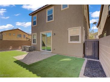 Landscaped backyard featuring artificial turf, a patio, and a sliding glass door for indoor-outdoor living at 9190 Wine Cellar Ave, Las Vegas, NV 89148