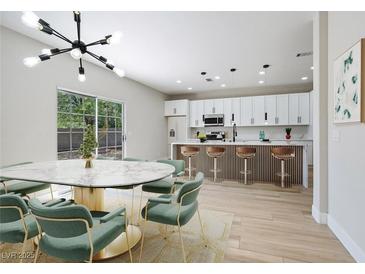 Open floor plan with modern kitchen, island with seating, and dining area with stylish light fixture at 1312 Pacific Terrace Dr, Las Vegas, NV 89128