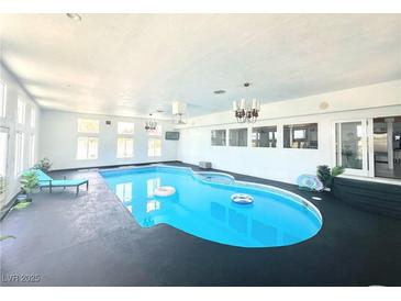 Bright indoor pool area features a blue in-ground pool, lounge chair, and recessed lighting at 2890 Belcastro St, Las Vegas, NV 89117