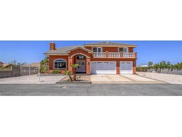 Two-story home with a terracotta facade, featuring a second-story balcony and arched entryway to the double-car garage at 420 Dakar St, Henderson, NV 89015