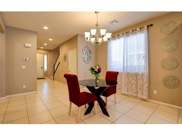 Bright dining area with modern chandelier, glass table, and comfortable red chairs at 462 Fortissimo St, Henderson, NV 89011