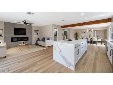 Spacious living room featuring a sleek fireplace, modern fan, and a stylish kitchen island at 356 Gulfport Ct, Las Vegas, NV 89145