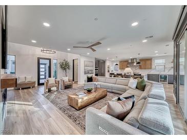 Bright open-concept living room featuring hardwood floors, a large sectional couch, and seamless access to the modern kitchen at 365 Crown Mesa Ave, Las Vegas, NV 89138