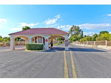 View of the community entrance featuring a red tile roof and neat landscaping at 5429 Sweet Shade St, Las Vegas, NV 89130