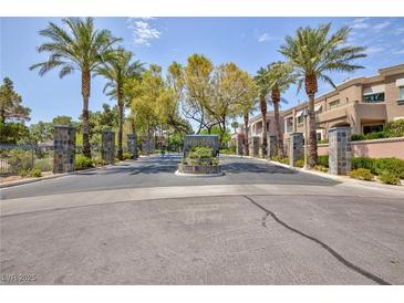 Community entrance featuring well manicured landscaping, towering palm trees, and attractive stone-clad posts at 9112 Vista Greens Way # 204, Las Vegas, NV 89134