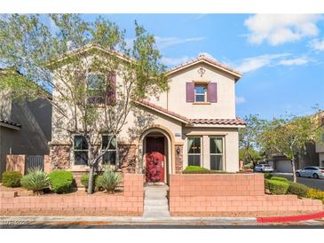 Charming two-story home featuring a red door, desert landscaping and a welcoming brick facade at 10917 Mount Pendleton St, Las Vegas, NV 89179