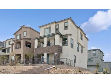 Modern three-story home showcasing stone accents, a balcony, and desert landscaping at 1474 Whistling Kite St, Las Vegas, NV 89138