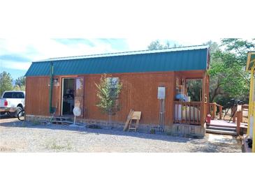 Cozy cabin with wood siding, teal roof, and open porch offering rustic charm at 1590 Landmark Ave, Pahrump, NV 89060