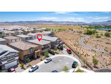 A bird's eye view of a community with well-maintained homes and a winding road. Mountains are in the distance at 330 Spring Dove Ave, Henderson, NV 89011