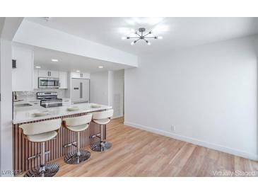 Modern kitchen with white cabinetry, stainless steel appliances, and a breakfast bar with seating at 3459 One Nation Ave, Las Vegas, NV 89121
