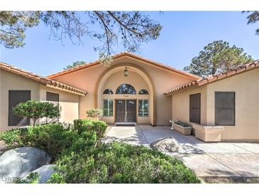 Inviting home featuring a grand entrance with a beautiful arched doorway and manicured landscaping at 7460 Buckskin Ave, Las Vegas, NV 89129
