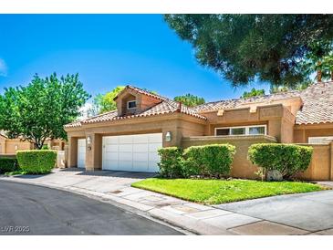 Charming home featuring a tile roof, two-car garage and manicured landscaping with vibrant green shrubs at 8236 Round Hills Cir, Las Vegas, NV 89113