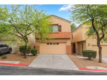 Two story home featuring a two-car garage, drought resistant landscaping and mature trees at 28 Yellow Flame Ave, North Las Vegas, NV 89084