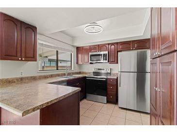 Cozy kitchen featuring stainless steel appliances, brown cabinets, and a window for natural light at 3936 Applecrest St, Las Vegas, NV 89108