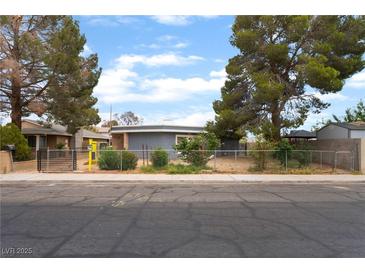 Charming single-story home with mature trees and a secure chain-link fence at 2301 Maverick St, Las Vegas, NV 89108