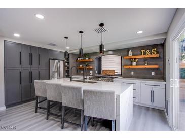 Modern kitchen with gray and white cabinets, stainless steel appliances, and a large center island at 6630 Virtuoso Ct, Las Vegas, NV 89139