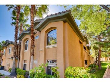 Beautiful condo building featuring desert landscaping with mature palm trees and lovely stucco at 1713 Sky Of Red Dr # 203, Las Vegas, NV 89128