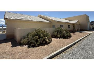 Tan single-story house featuring desert landscaping and a white tiled roof at 4831 W Bell Vista Ave, Pahrump, NV 89060