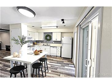 Bright kitchen boasts white cabinetry, stainless steel appliances, and a center island with seating at 708 Fernwood Ln, Las Vegas, NV 89169