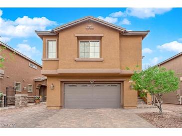 Two-story home featuring a brown garage door, complementary tan-colored walls, and a well-maintained yard at 765 Crimson Peak Pl, Henderson, NV 89011