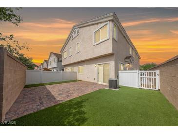 A fenced backyard with faux grass, a brick patio, and the home's rear entrance at 9312 Straw Hays St # 103, Las Vegas, NV 89178