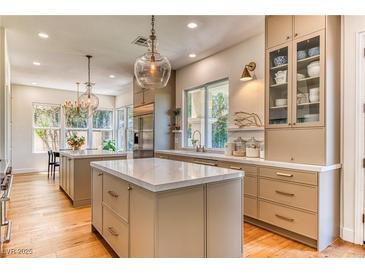 Bright eat-in kitchen with double islands, wood floors, stainless steel appliances, and modern lighting fixtures at 1235 Panini Dr, Henderson, NV 89052