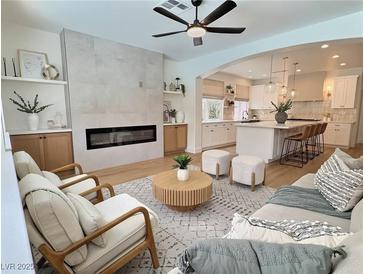 Bright living room with fireplace, ceiling fan, modern furnishings, and open access to a gourmet kitchen at 1624 Ravanusa Dr, Henderson, NV 89052
