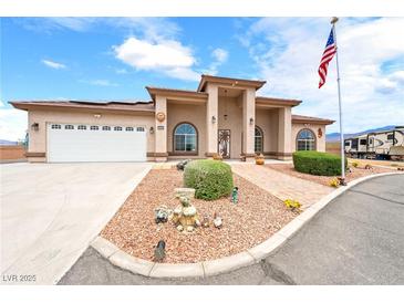 Charming single-story home featuring an arched entrance, desert landscaping, RV parking, and an American flag at 2020 S Omaha Ave, Pahrump, NV 89048