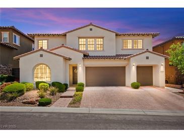 Inviting two-story home with a terracotta tile roof, manicured landscaping and brick paved driveway at 454 Rosina Vista St, Las Vegas, NV 89138
