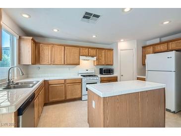 Traditional kitchen featuring wood cabinetry, white appliances and white tile countertops, backsplash and island at 4744 Deer Forest Ave, Las Vegas, NV 89139