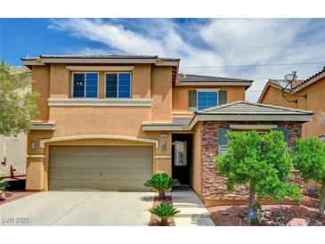 Two-story home featuring a two-car garage, manicured lawn and stone accents, offering both curb appeal and practicality at 7372 S Palo Real Ct, Las Vegas, NV 89179