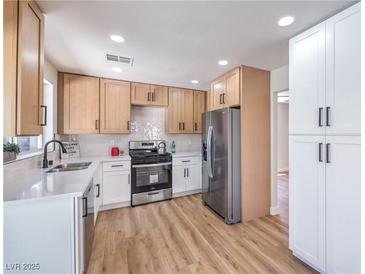 This bright kitchen features stainless steel appliances, white countertops, light cabinets, and modern hardware at 9321 Dancing Daffodil Ave, Las Vegas, NV 89129