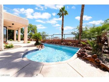 Inviting backyard pool with rock features and mature palms, perfect for relaxation at 1016 Eaglewood Dr, Las Vegas, NV 89144
