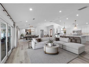 Open living room featuring a large sectional, dining area, and a modern kitchen at 2250 Bowie Cir, Henderson, NV 89014