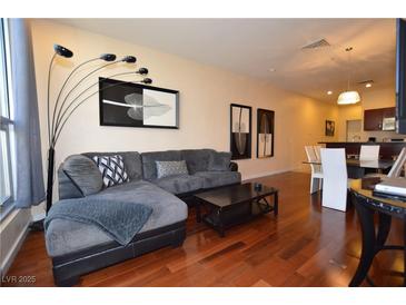 Bright living room featuring wood floors, gray sectional couch, modern decor, and views of kitchen and dining room at 4585 Dean Martin Dr # 205, Las Vegas, NV 89103