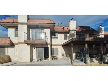 Beige, two-story condo with a red tile roof, balcony, and covered patio at 671 Bourbon St, Pahrump, NV 89048