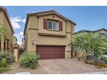 Charming home featuring a two-car garage, complemented by desert landscaping and a brick driveway at 10974 Cheshire Woods Ave, Las Vegas, NV 89166
