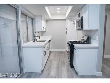 This kitchen has white cabinets, a black faucet, modern appliances, and plenty of counter space at 1440 Vegas Valley Dr # 3, Las Vegas, NV 89169