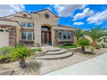 Inviting stucco home featuring stone accents, a curved entry, and lush landscaping with palm trees at 2168 Big Bar Dr, Henderson, NV 89052