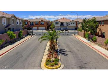 Community street view with palm trees, landscaped median, and gated entry to a neighborhood of modern homes at 23 Hudson Canyon St # 3, Henderson, NV 89012