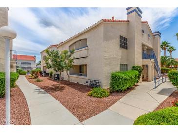 Low-rise condo with well-maintained landscaping, a red tile roof, blue railing, and multiple windows under a partly cloudy sky at 2725 S Nellis Blvd # 2168, Las Vegas, NV 89121