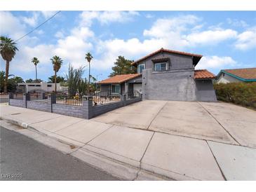Inviting gray two-story home featuring a well-kept yard, decorative fence and mature palms at 3400 Sioux Way, Las Vegas, NV 89169